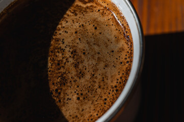  Close-up of fresh coffee with rich crema in a mug on a rustic wooden table. Warm, inviting natural...