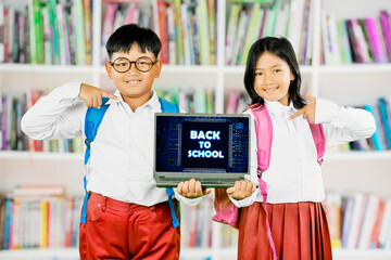 Happy Asian School Kids Pointing at Laptop with Back to School Text in Library