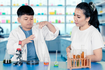 Asian Boy Doing Science Experiment with Teacher in Chemistry Laboratory