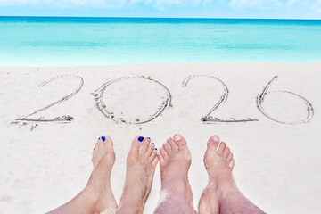 Couple Relaxing on Beach with "2026" Written in Sand