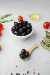 Bowl of black olives with tomatoes asparagus and cooking ingredients