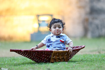Charming baby boy dressed in a stylish blue and white outfit with a bow tie, sitting inside a...
