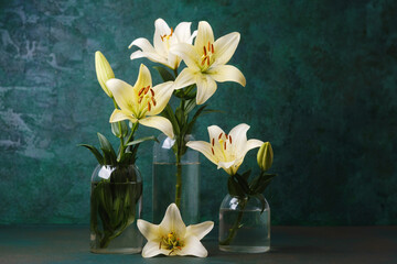 Elegant white lilies in glass vase on green background – floral decor or wellness concept
