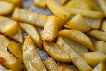 Homemade golden potato wedges baked in the oven, close-up