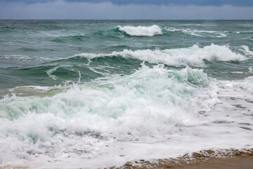 crashing waves on the beach in the evening