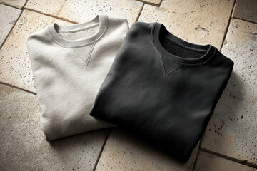 Two folded blank sweatshirts in gray and cream are displayed on a textured surface for design inspiration. The flatlay showcases clean lines