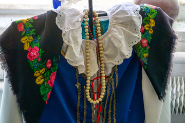 Traditional folk costume with a white lace blouse, colorful floral shawl, and wooden beads. Element...