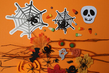 Halloween with skull, ticks, orange maple leaves, bats, spiders on orange background with space for text.