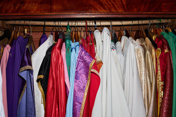 Assorted ceremonial vestments hanging on rack in church wardrobe, various ornate garments used by...