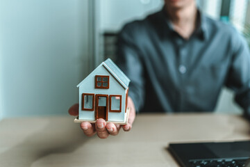 Home salesman, insurance salesman Holding a house in hand. Assets, real estate, loans and property...
