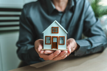 Home salesman, insurance salesman Holding a house in hand. Assets, real estate, loans and property...