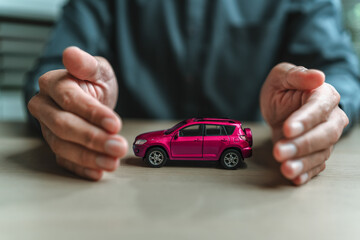Businessman's hand gestures to protect a car. Image represents the concept Insurance, protection,...