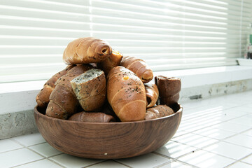 Assortment of freshly baked bread and croissants in a wooden bowl