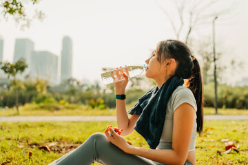 A woman dressed in workout clothes is drinking water during a break from exercising. Sport,...