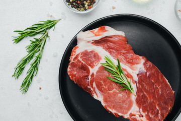 Pork steak with rosemary on black plate with spices