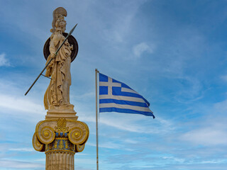 Elegant marble statue of Athena, the Greek Goddess of wisdom and science, on an Ionic column beside the Greek flag. Travel to Athens, Greece.