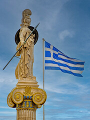 Elegant marble statue of Athena, the Greek Goddess of wisdom and science, on an Ionic column beside the Greek flag. Travel to Athens, Greece.