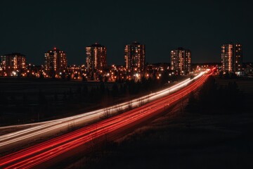 Nighttime cityscape with illuminated buildings and light trails on a highway