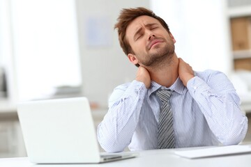Man experiencing neck pain while working at a desk in a bright office environment