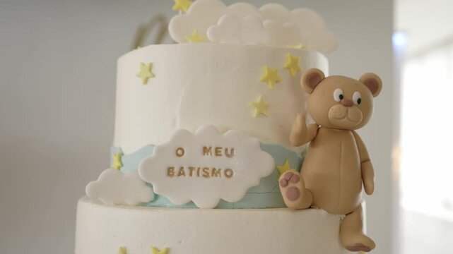 white baptism cake decorated with fondant bear, yellow stars, and cloud reading 'o meu batismo'