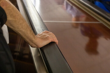 elderly man hand holding railing on escalator in subway