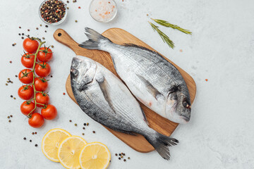 Close up of dorado fish tomatoes lemon and spices on cutting board