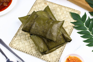 Buras, Indonesian traditional rice cakes from Makassar, South Sulawesi. Buras made from rice, coconut milk and salt wrapped with banana leaves and served with savory soup and beef or chicken.