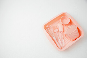 Pink silicone baking utensils set on tray over white background
