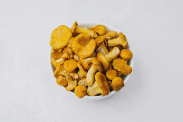 Freshly harvested chanterelle mushrooms in a white bowl on a light surface