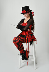 Burlesque circus performer, fantasy female model in halloween jester clown costume with top hat,...