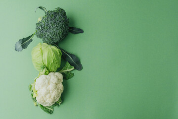 Cabbage, broccoli and cauliflower vegetables on green table top view