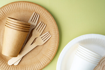 Scattered eco-friendly paper cups and forks on green background