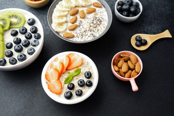 Assorted breakfast oatmeal bowls with fruits chia seeds and almonds on black background
