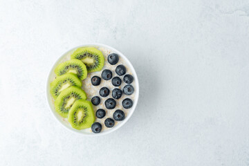 Oatmeal breakfast bowls with fruits and grains on white surface