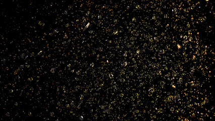 Sparkling water droplets glimmering on dark surface