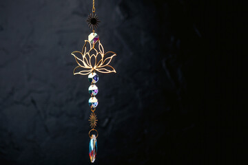 Golden lotus ornament with crystal beads and sun charm on dark background