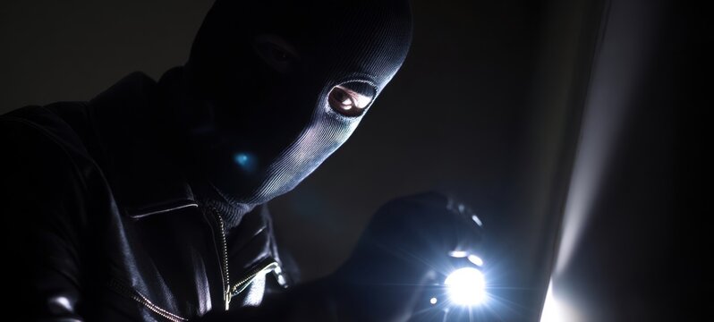The burglar using a flashlight in a dark, suspenseful setting. - Powered by Adobe