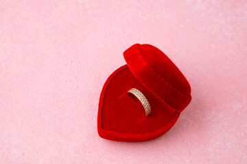 Paved diamond ring in heart-shaped red box on pink background