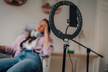 Ring light and microphone ready for recording with influencer relaxing in background