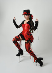 Burlesque circus performer, fantasy female model in halloween jester clown costume with top hat,...