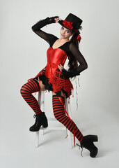 Burlesque circus performer, fantasy female model in halloween jester clown costume with top hat,...