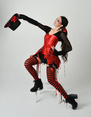 Burlesque circus performer, fantasy female model in halloween jester clown costume with top hat,...