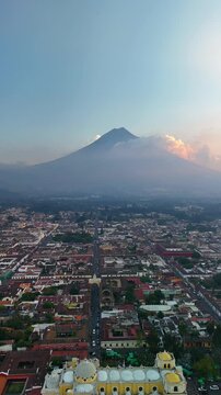 Vertical Drone view of the Iglesia de la Merced church and the Santa Catalina Arch in Antigua, Guatemala. View of the Agua volcano.	
