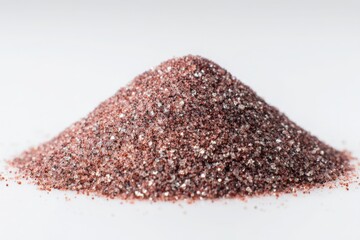 A mound of shiny rose gold glitter powder against a plain white background in a studio shot