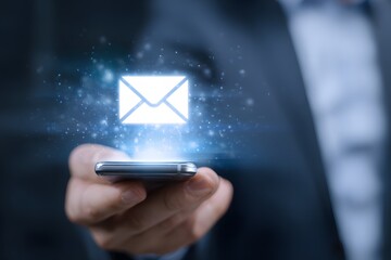 A businessman holding a smartphone with a glowing email icon representing digital communication