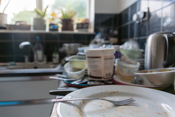 A kitchen worktop covered in unwashed crockery and recycling. Copy space.
