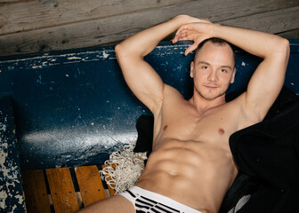 Young attractive man relaxing on a small boat. Fisherman after fishing at the old pier.
