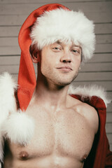 Young attractive man with athletic body posing in Santa Claus costume.