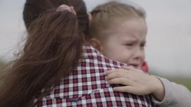 The mother calms the child, the little kid is crying, the mother regrets the crying baby, to be offended and upset at the people around, the parent hugs the girl, the concept of family life.