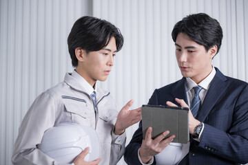 Men in construction management work clothes and suits checking materials at a general contractor or...